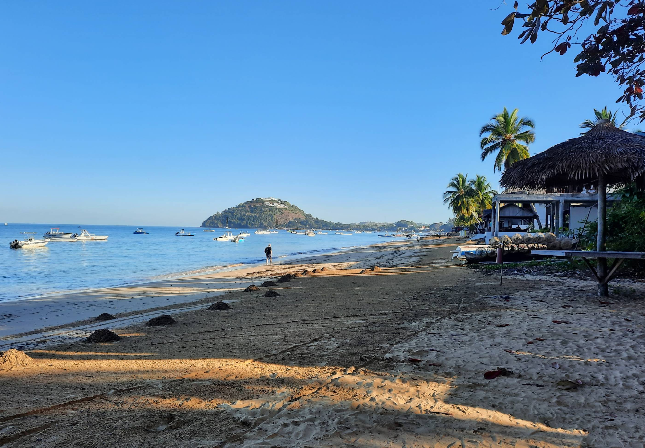 playa de arena blanca con lanchas y tapasoles de palma ubicada en nosy be en madagascar